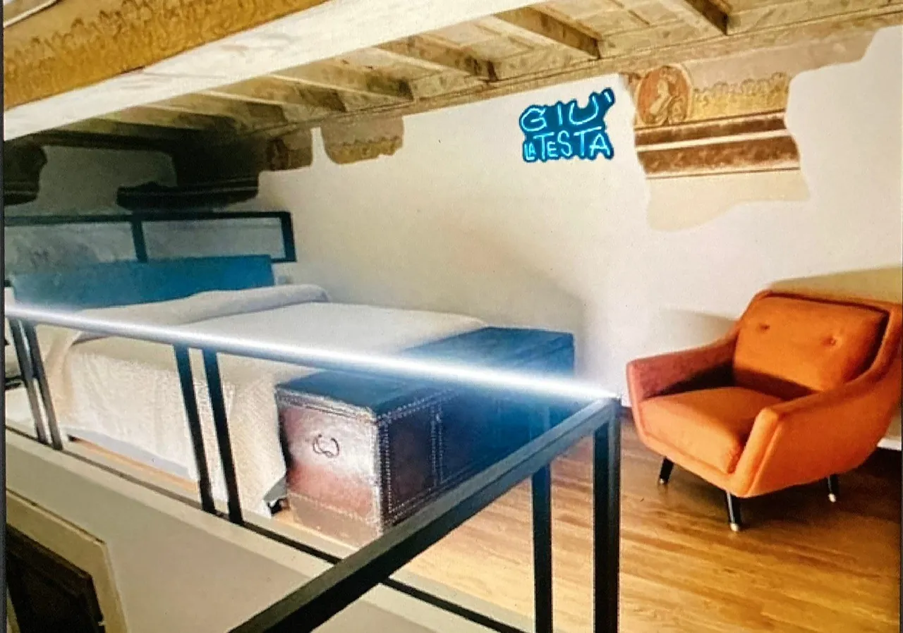 Il letto sul soppalco con l'insegna al neon